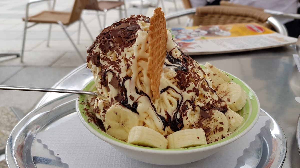 Bananensplit in einer grünen Schale mit Schlagobers, Schokoladensoße und Waffel